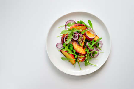 Vegetarian gourme salad made of grilled peaches slices, red onion and arugula, top viewの写真素材
