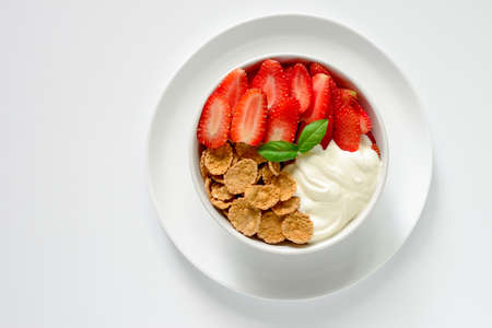 Cereal or corn flakes, strawberries and yogurt bowl for breakfast, view from high angleの写真素材