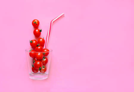 Tomato juice or fresh or smothies or any drink concept, cherry tomatoes in a glass with a straw, flat lay, view from above photo with a space for a textの写真素材