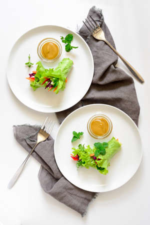 Lettuce vegetarian wraps or rolls stuffed with freshly chopped juicy vegetables and herbs, served with sauce and decorated with fresh mint leaves, view from aboveの写真素材