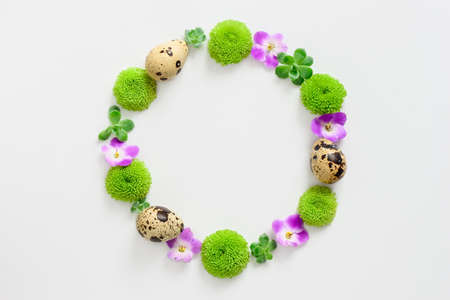 Easter greeting concept, wreath made of flowers and eggs, space for agreeting text, view from aboveの写真素材