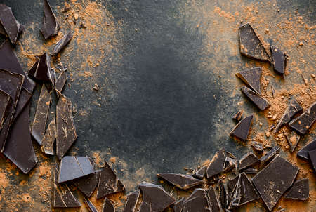 Dark chocolate pieces crushed on a dark surface, view from above, space for a textの写真素材