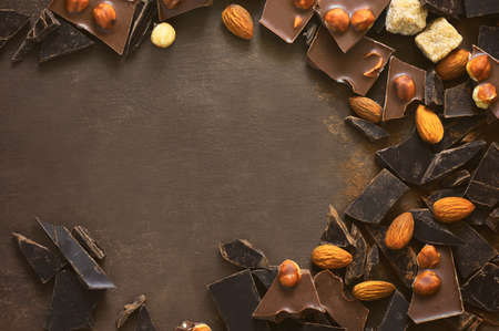 Various types of chocolate pieces crushed on a dark surface, chocolate background with a space for a text, view from aboveの写真素材