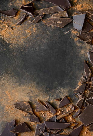 Dark chocolate pieces crushed on a dark surface, view from above, space for a textの写真素材