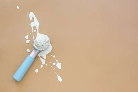 Ice cream minimal background with a space for a text, melting ice cream ball in a scoop laid on splashes, view from aboveの写真素材