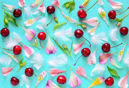 Romantic background, summer cherries, white feathers and flower petals flat lay