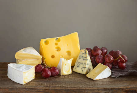 Cheese in assortment. Various kinds of soft artisan aged brie cuts,  blue cheese and Maasdam on a...