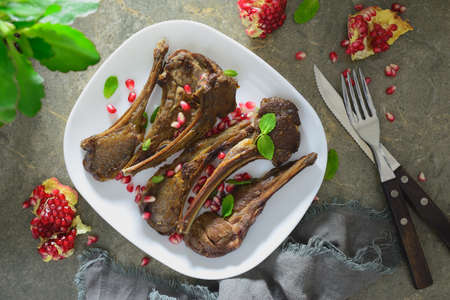 Lamb chops served with pomegranate and mint, flat lay composition of a table setting, overhead viewの写真素材