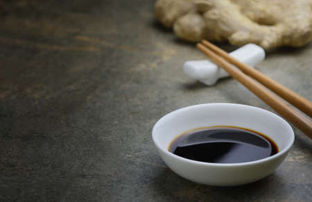 Soya sauce in a white bowl on a kitchen dark stone table top, front view background with a space for a textの写真素材