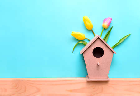 Spring concept background with birdhouse decorated with tulips, composition with a space for a textの写真素材