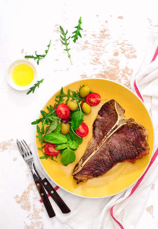 T-bone steak cooked and ready to eat, served on a plate, overhead viewの写真素材