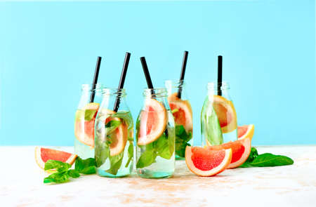 Pink grapefruit and fresh basil infused drink  in bottles, spa fruit water, or summer party alcoholic jin tonic cocktail served in small shots, front viewの写真素材