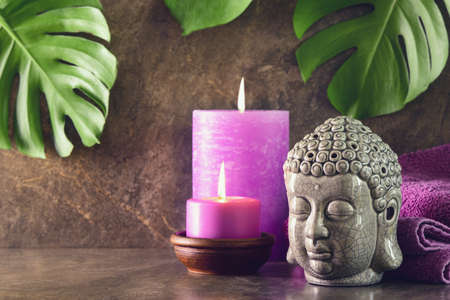 Spa and massage relaxing treatment with aroma birning candles and Buddha head statue concept, front view, space for a textの写真素材