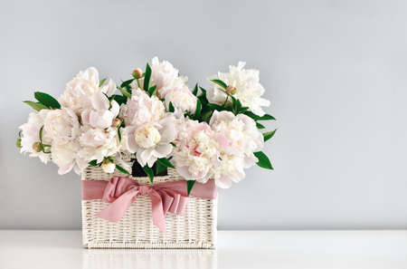 Peonies in white rustic basket, wedding card or Mother's Day concept.の写真素材