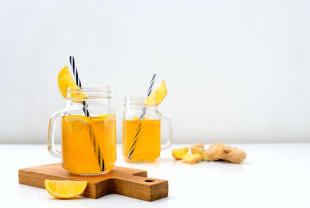 Ginger and lemon combucha detox drink in two jars with straws, front view, space for a textの写真素材