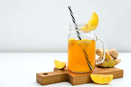Ginger and lemon combucha detox drink in a jar with a straw, front view, space for a textの写真素材