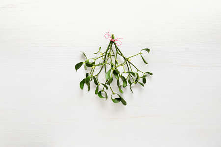 Mistletoe traditional Christmas bunch on white wooden background, flat lay, space for a greeting...