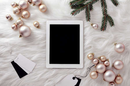 Christmas social media concept, fashion blogging or shopping online during Christmas holidays, white tablet lying down on a faux fur, view from above, space for a textの写真素材