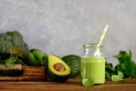 Avocado base home made green smoothies with vegetable leafy greens in a jar standing on a kitchen table, front viewの写真素材