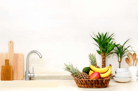 Home modern kitchen table top decorated with summer exotic fruits in a basket and home tropical...