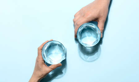 Woman and man are holding glasses full of clear purified water, minimalist  concept, elevated view compositionの写真素材