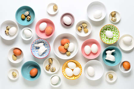 Easter home decor concept, view from above on various types of plates and bowls filled with natural eggsの写真素材