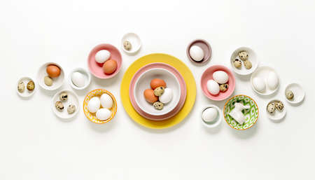 Easter home decor concept, view from above on various types of plates and bowls filled with natural eggs, blank space for a textの写真素材