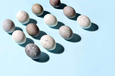Easter eggs minimal concept, flat lay of naturally painted eggs lying diagonally, with strong sunshine shadowの写真素材