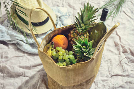 Beach picnic bag with fruits and wine standing on a cotton beach rugの写真素材