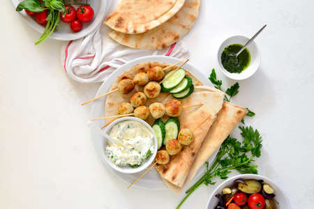 Greek turkey meatballs with pita and tzatziki, top down view on table setting with meatballs dish and fresh vegetablesの写真素材