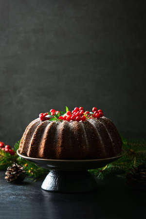 Christmas homebaked dark  chocolate bundt cake decorated with powdered sugar and fresh berries,...