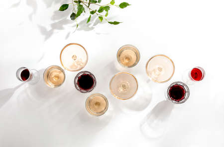 Rose wine assortment, top-down view of various wine glasses full of rose and red wine, standing on a white table surface  reflecting soft sunshine raysの写真素材