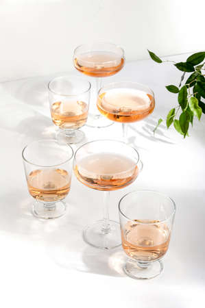 Rose wine assortment, front view of various wine glasses full of rose wine, standing on a white table surface  reflecting soft sunshine raysの写真素材
