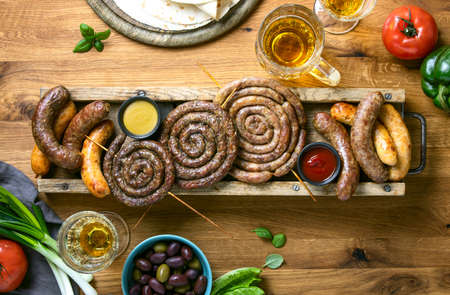 Sausages served with tomato sauce and mustard on a rustic board, summer outdoor party culinary idea, top down viewの写真素材