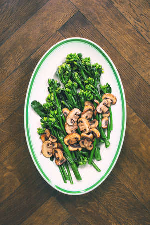 Stir-fried broccolini with mushrooms in an oval dish, simple vegetarian side dish recipe idea, overhead viewの写真素材