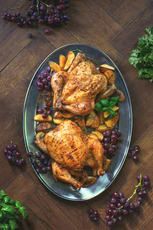 Oven-roasted chicken served with baked potato on an oval dish, holiday culinary concept, overhead viewの写真素材