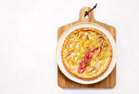 Rhubarb open faced round pie served on a wooden cutting board, overhead view, summer season culinary conceptの写真素材