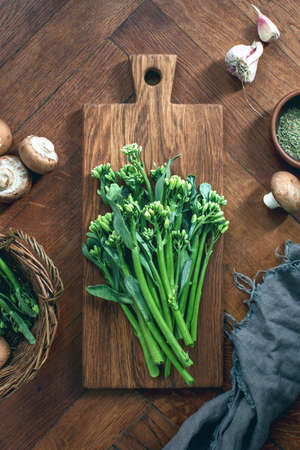 Broccolini fresh bunch on a rustic cutting board ready for cooking, top down view healthy eating culinary conceptの写真素材
