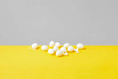 Easter minimal background with eggs lying down on the bright yellow surface with a huge grey colored space for a textの写真素材