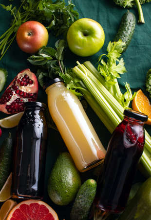Fresh detox fruit and vegetable smoothies or juice in bottles with various ingredients aroundの写真素材