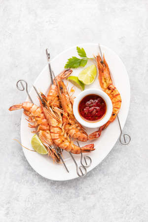 Grilled tiger prawns skewers served with hot barbeque sauce, summer outdoor kitchen recipe, top down viewの写真素材