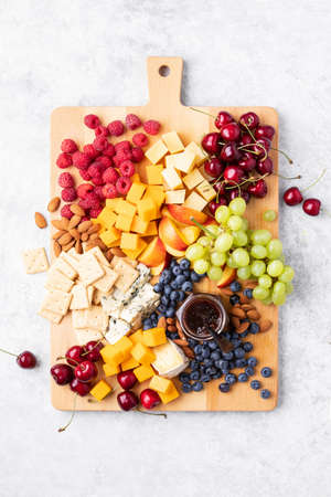 Charcuterie or cheese board with season berries, summer party snack idea, top down viewの写真素材
