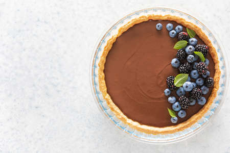 Dark chocolate mousse tart decorated with fresh blueberries and the mint, view from above, copy space for a textの写真素材