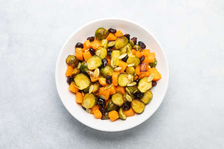 Roasted brussels sprouts salad with maple butternut squash, pumpkin seeds, and cranberries, top down viewの写真素材