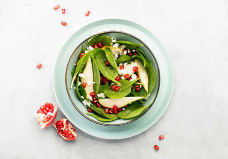 Spinach and pear salad with goat cheese and pomegranate seeds, top down viewの写真素材