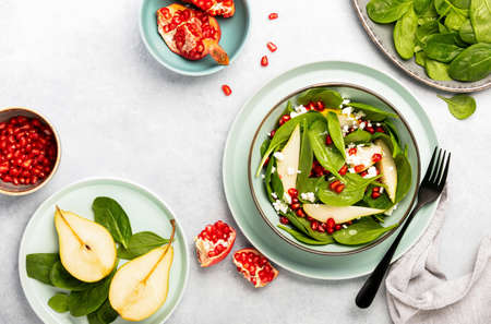 Spinach and pear salad with goat cheese and pomegranate seeds, top down viewの写真素材