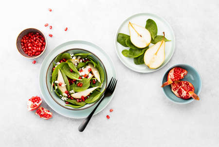 Spinach and pear salad with goat cheese and pomegranate seeds, top down viewの写真素材