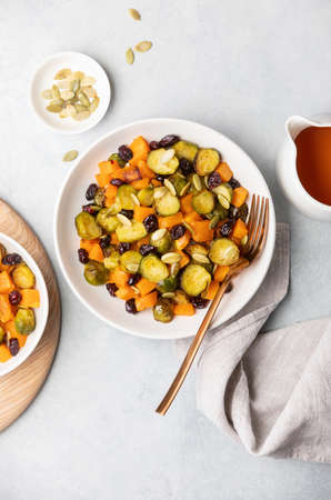 Roasted brussels sprouts salad with maple butternut squash, pumpkin seeds, and cranberries, top down viewの写真素材