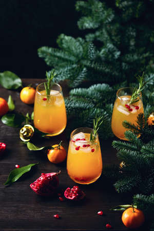 Tangerine pomegranate Christmas party fizz cocktail standing on a dark festive decorated tableの写真素材