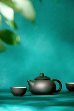 Natural green tea concept, dark teapot, and tea bowls front view,   copy space for a text above